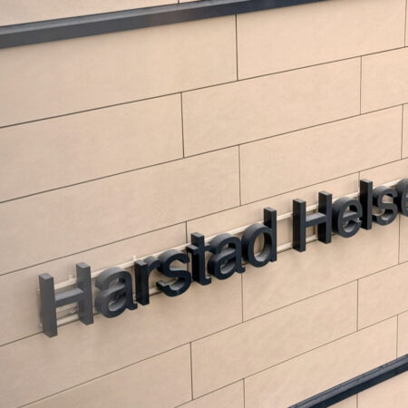 Detalj av fasaden till Harsatad Helsehus, men fikus på skriften på byggen "Harstad Helsehus"