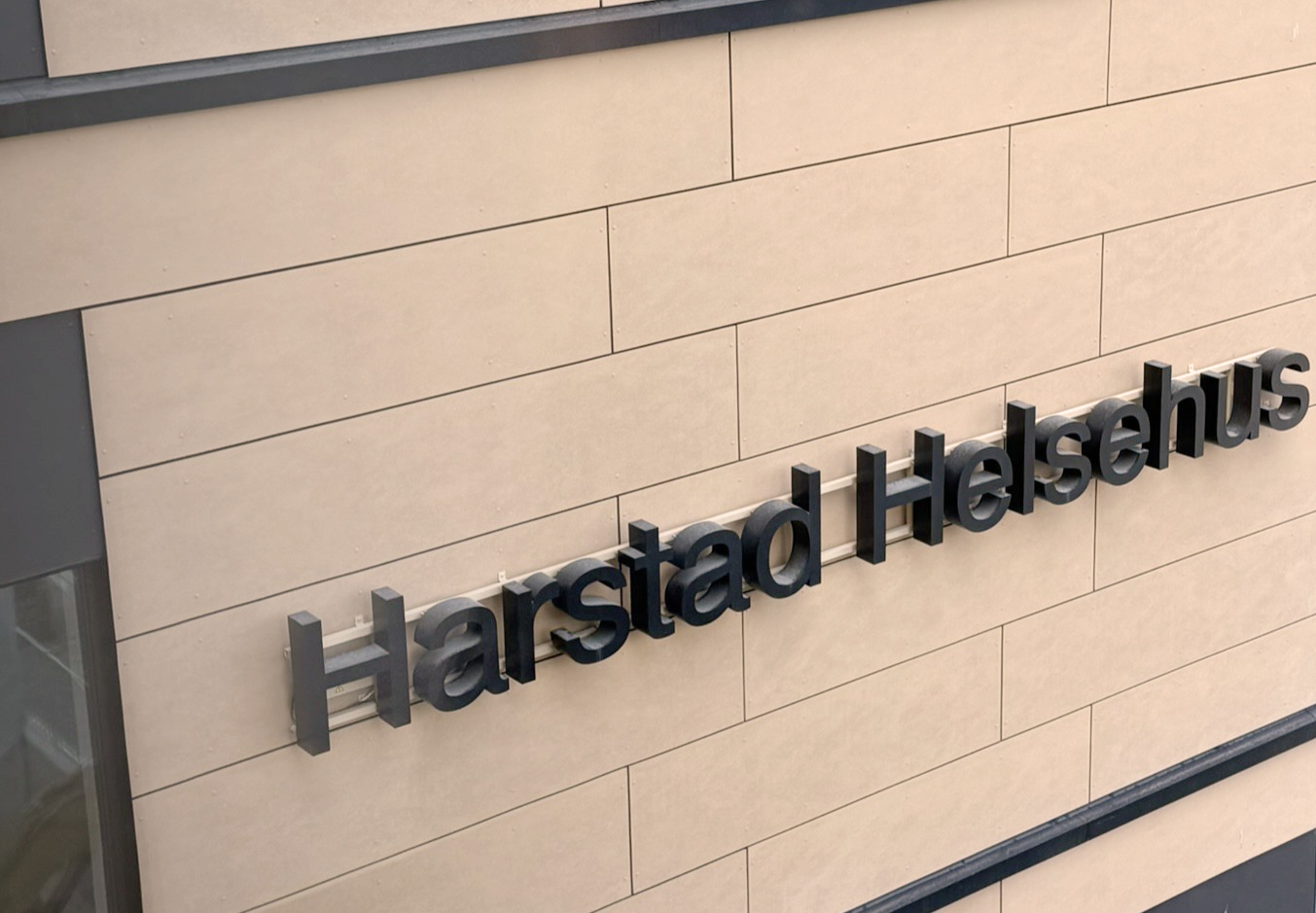 Detalj av fasaden till Harsatad Helsehus, men fikus på skriften på byggen "Harstad Helsehus"